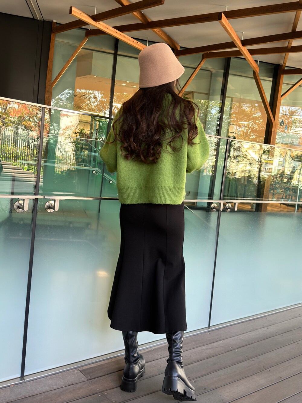 グリーン系のニット/セーター、ブラック系のスカート、ベージュ系のハットを着用したレディースの秋コーディネートの3枚目の写真