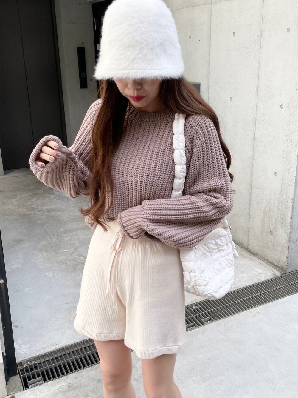 イエロー系のニット/セーター、ホワイト系のダウンベスト、ホワイト系のその他パンツを着用したレディースの秋コーディネートの3枚目の写真