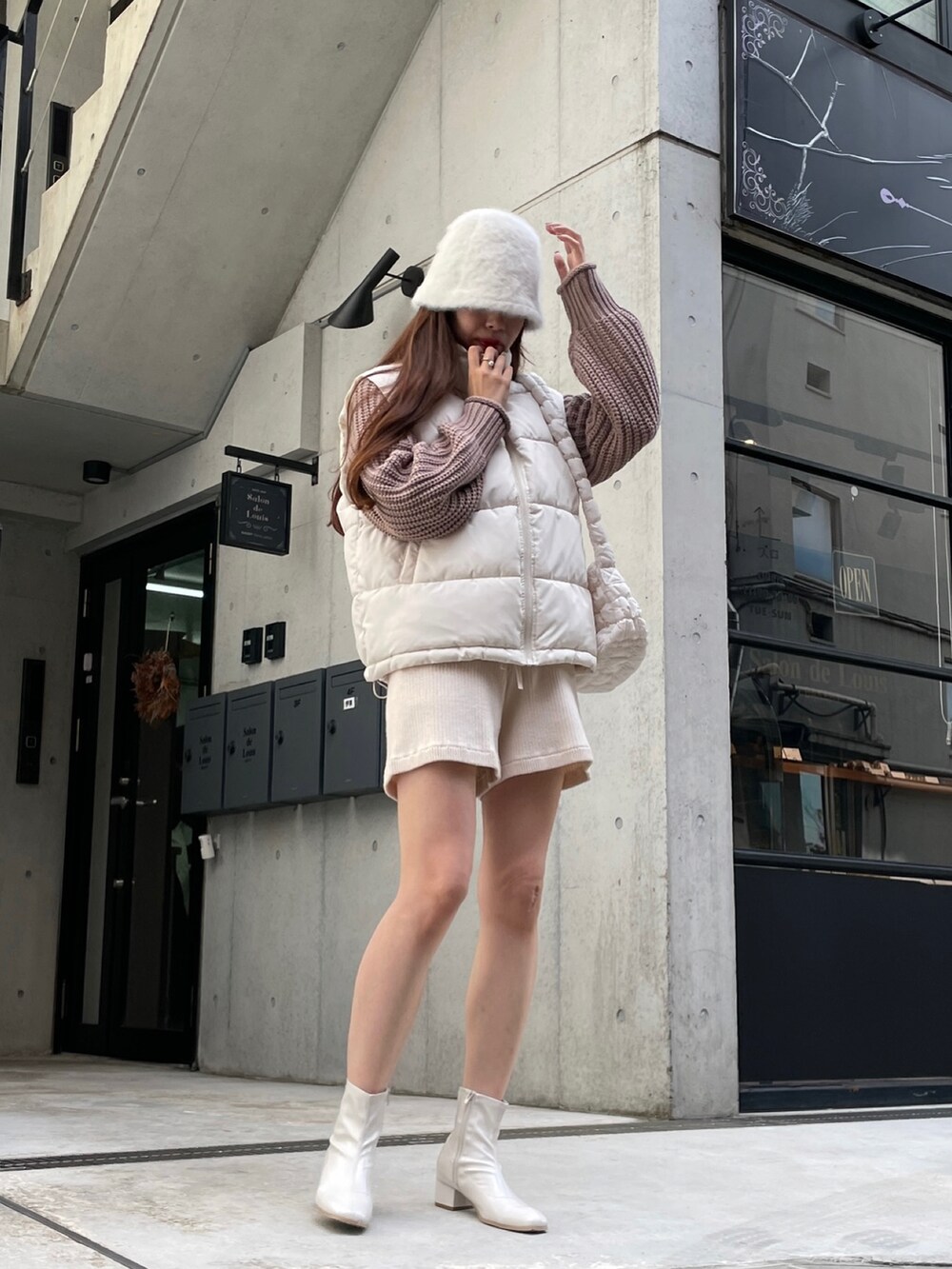 イエロー系のニット/セーター、ホワイト系のダウンベスト、ホワイト系のその他パンツを着用したレディースの秋コーディネートの2枚目の写真