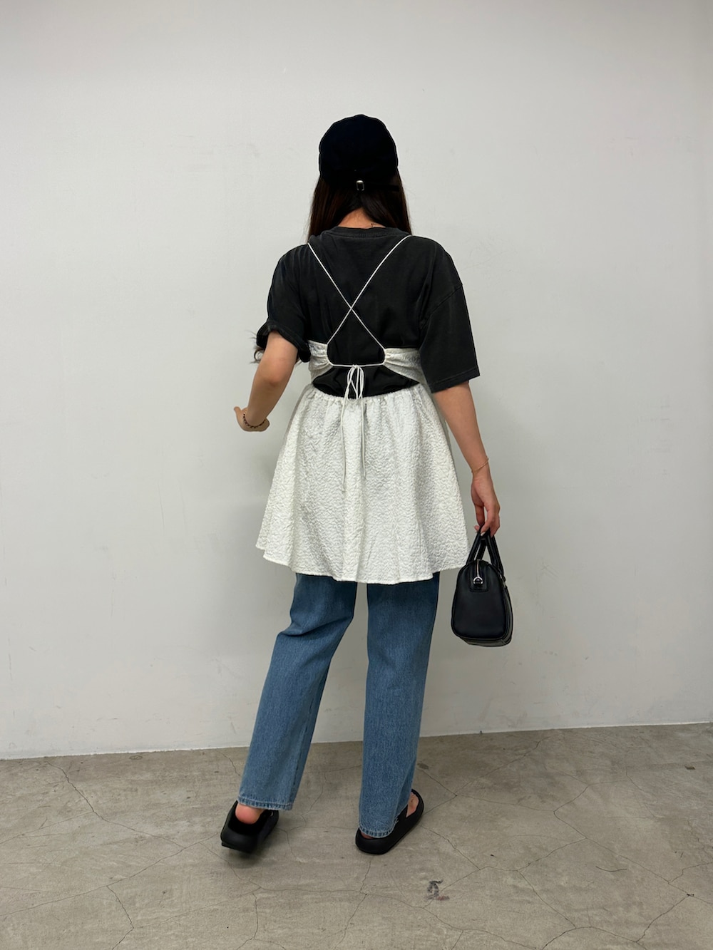 ブラック系のTシャツ/カットソー、ホワイト系のワンピース、ブルー系のデニムパンツを着用したレディースの春コーディネートの2枚目の写真