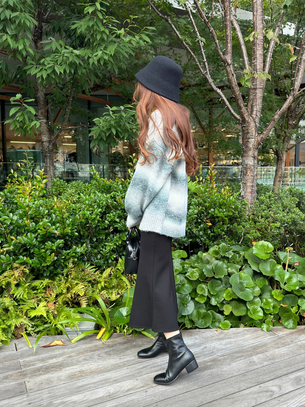 グレー系のTシャツ/カットソー、ブラック系のスカート、ブラック系のブーツを着用したレディースの冬コーディネートの3枚目の写真