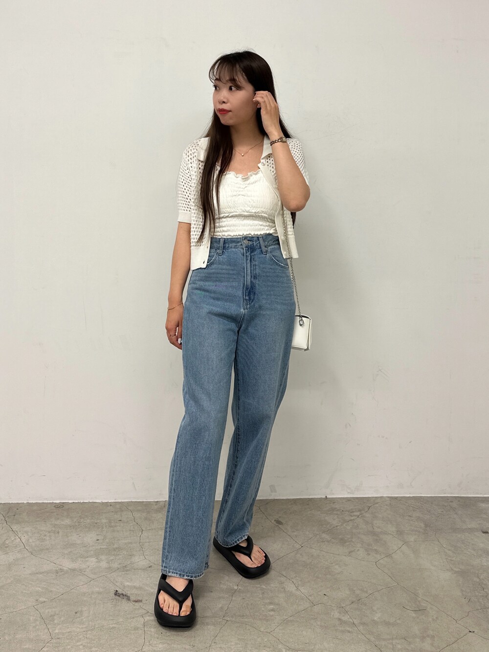 ホワイト系のカーディガン/ボレロ、ブルー系のデニムパンツ、ブラック系のサンダルを着用したレディースの春コーディネートの2枚目の写真