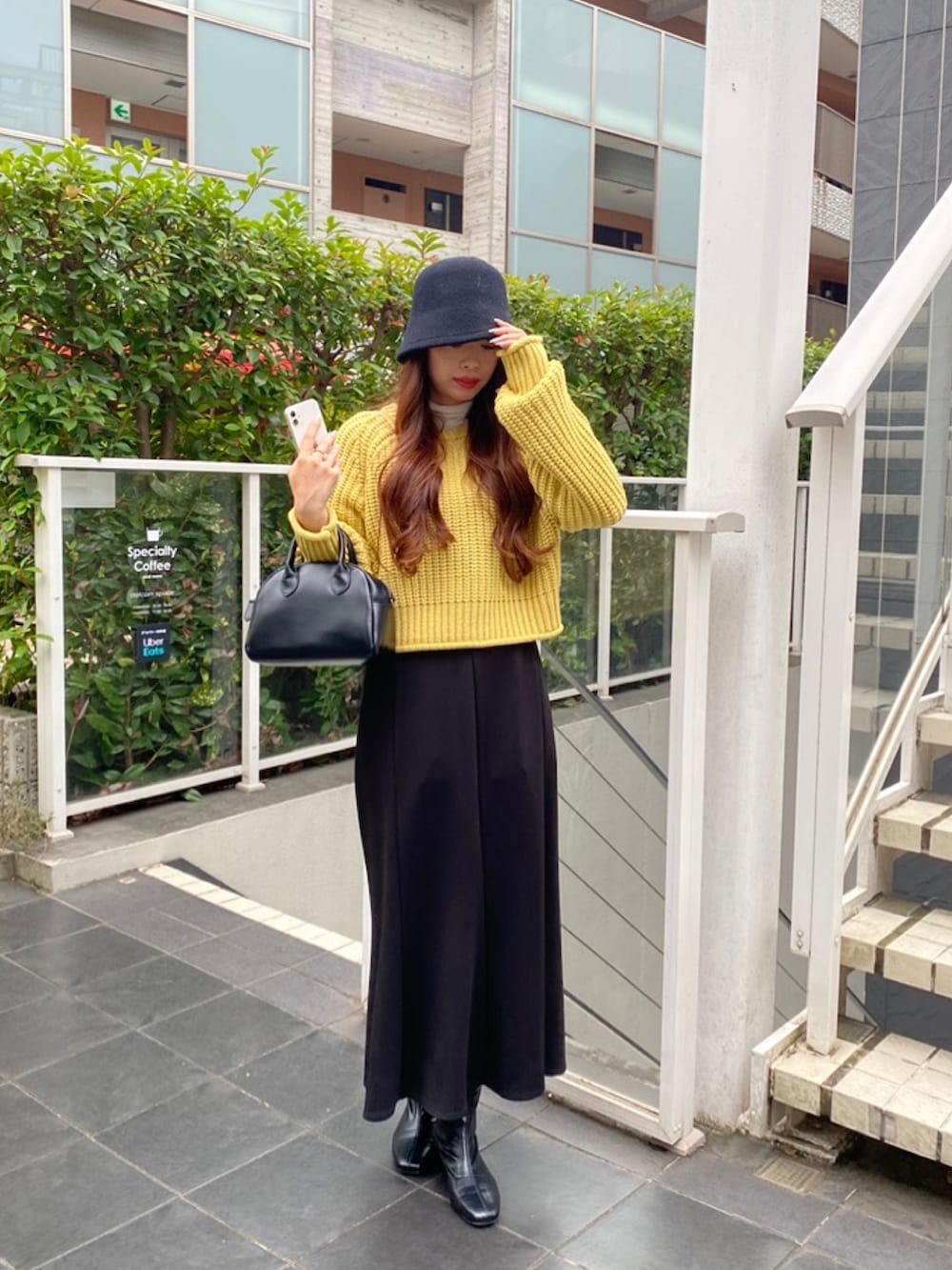 イエロー系のニット/セーター、ホワイト系のTシャツ/カットソー、ブラック系のスカートを着用したレディースの秋コーディネートの2枚目の写真