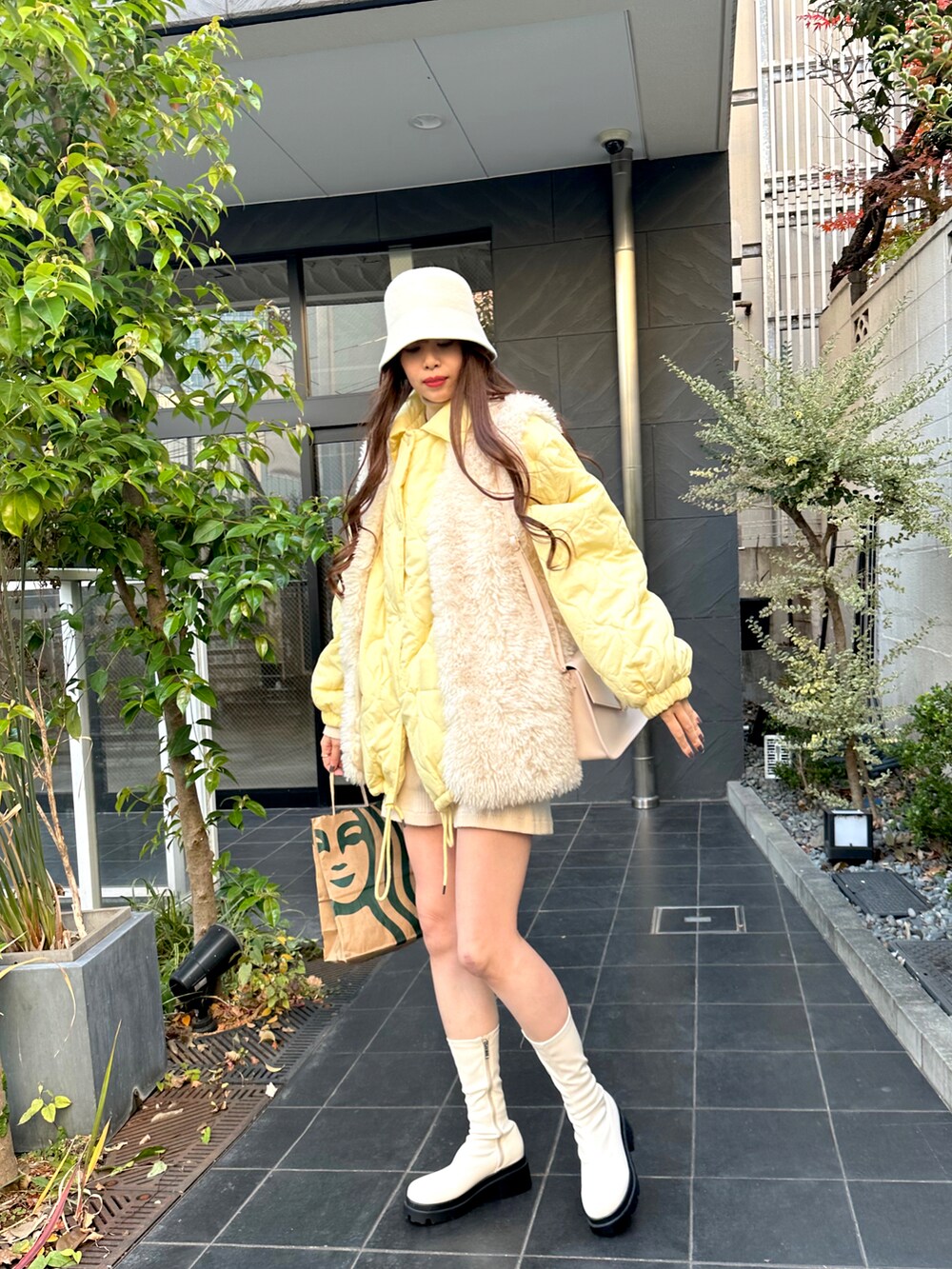 イエロー系のブルゾン、ホワイト系のベスト、ホワイト系のその他パンツを着用したレディースの冬コーディネートの2枚目の写真