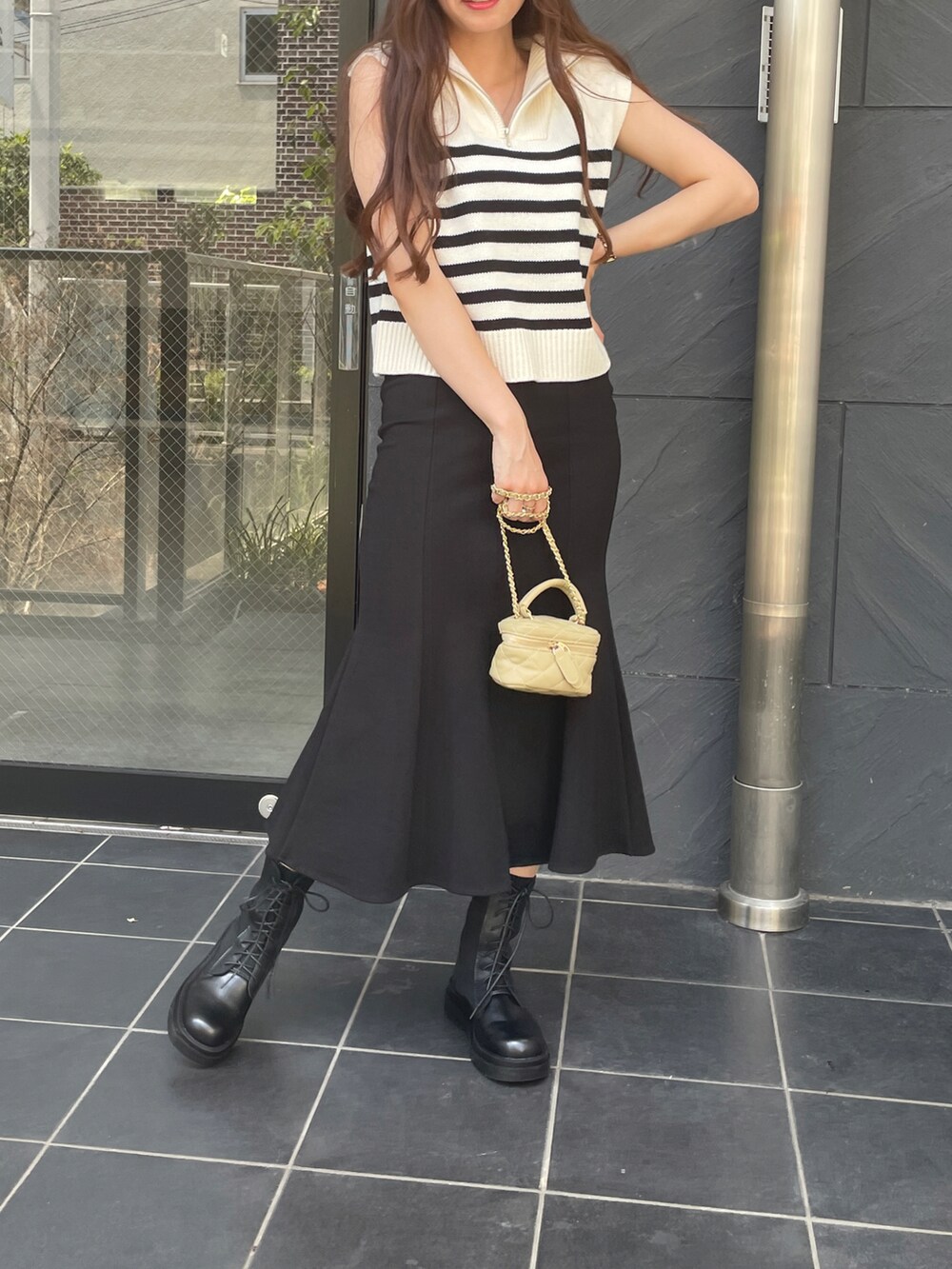 ホワイト系のベスト、ブラック系のスカートを着用したレディースの夏コーディネートの2枚目の写真