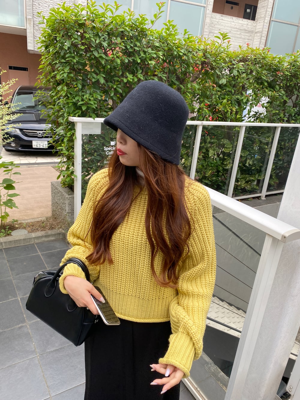 イエロー系のニット/セーター、ホワイト系のTシャツ/カットソー、ブラック系のスカートを着用したレディースの秋コーディネートの3枚目の写真