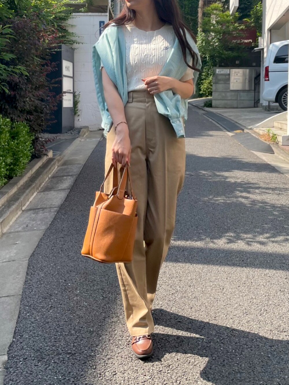 ベージュ系のチノパンツ、ホワイト系のニット/セーターを着用したレディースの夏コーディネートの2枚目の写真