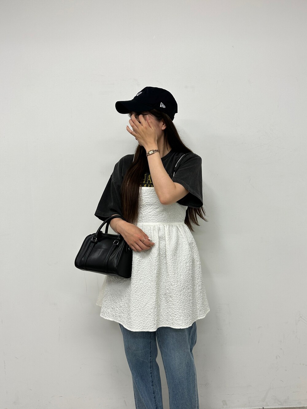 ブラック系のTシャツ/カットソー、ホワイト系のワンピース、ブルー系のデニムパンツを着用したレディースの春コーディネートの3枚目の写真