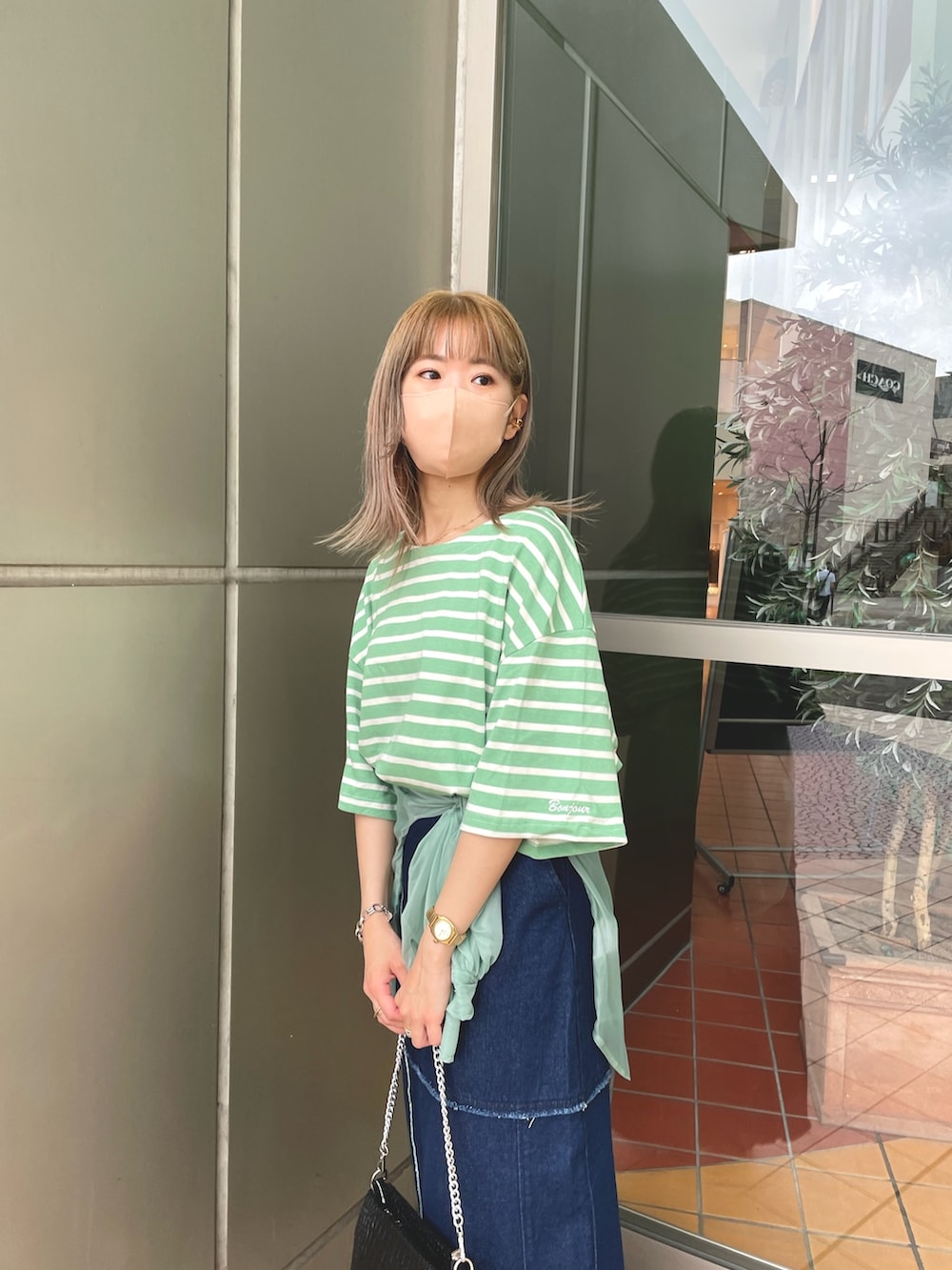 グリーン系のTシャツ/カットソー、ブルー系のデニムスカートを着用したレディースの夏コーディネートの2枚目の写真