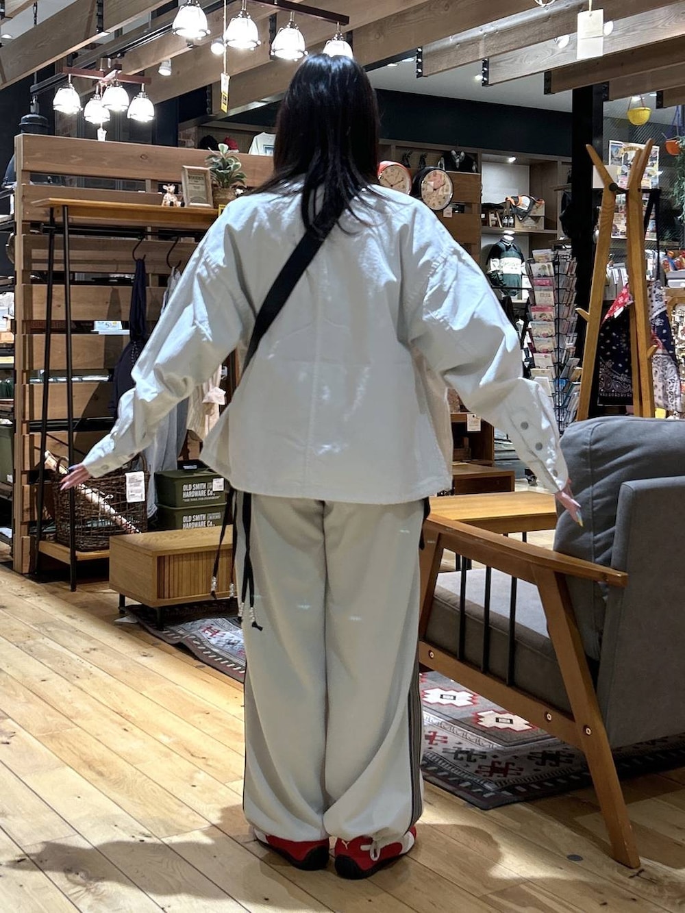 レッド系のスニーカー、ブラック系のショルダーバッグ、ベージュ系のカバーオールを着用したレディースの春コーディネートの4枚目の写真