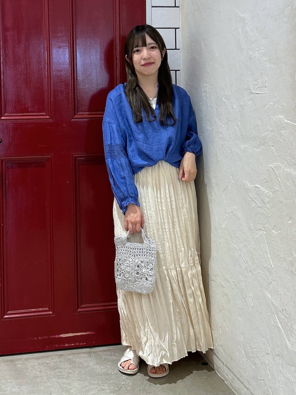 グレー系のショルダーバッグ、ベージュ系のスカート、ベージュ系のサンダルを着用したレディースの夏コーディネートの2枚目の写真