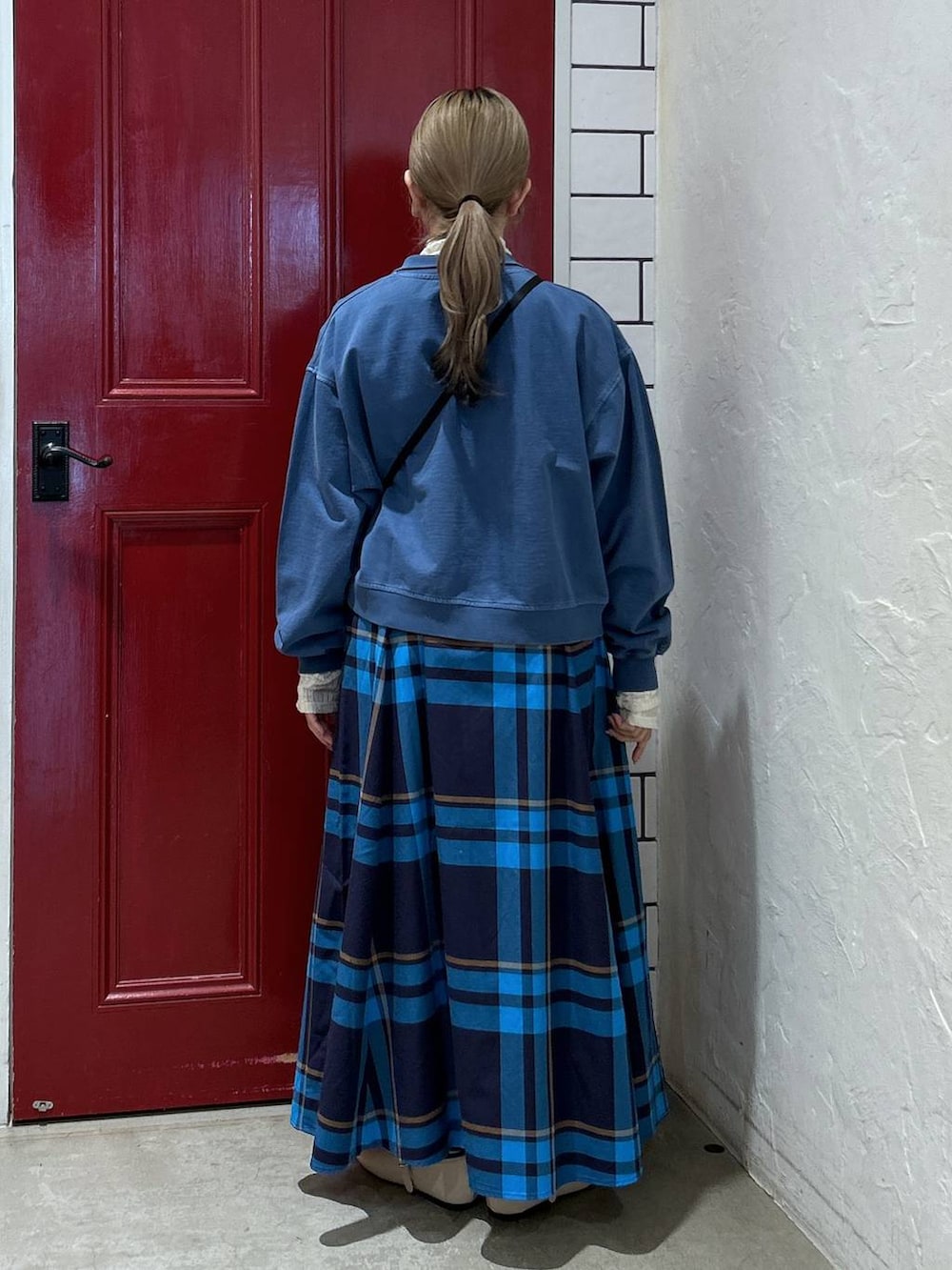 ブルー系のスウェット、ベージュ系のショルダーバッグ、ホワイト系のパンプスを着用したレディースの春コーディネートの3枚目の写真