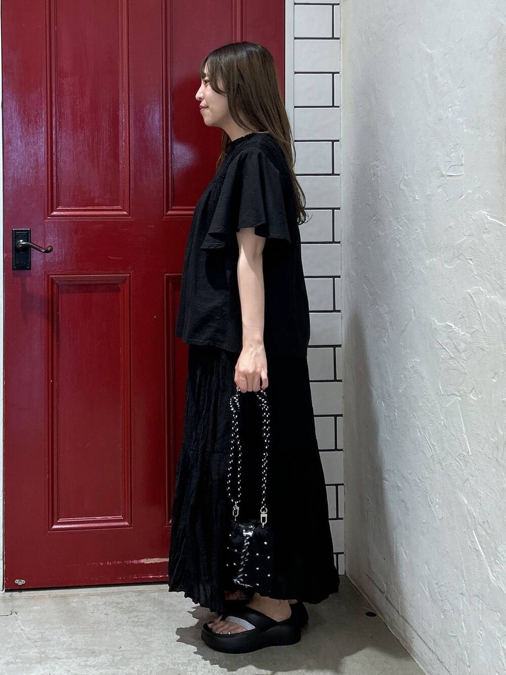 ブラック系のショルダーバッグ、ブラック系のサンダル、ブラック系のスカートを着用したレディースの夏コーディネートの3枚目の写真