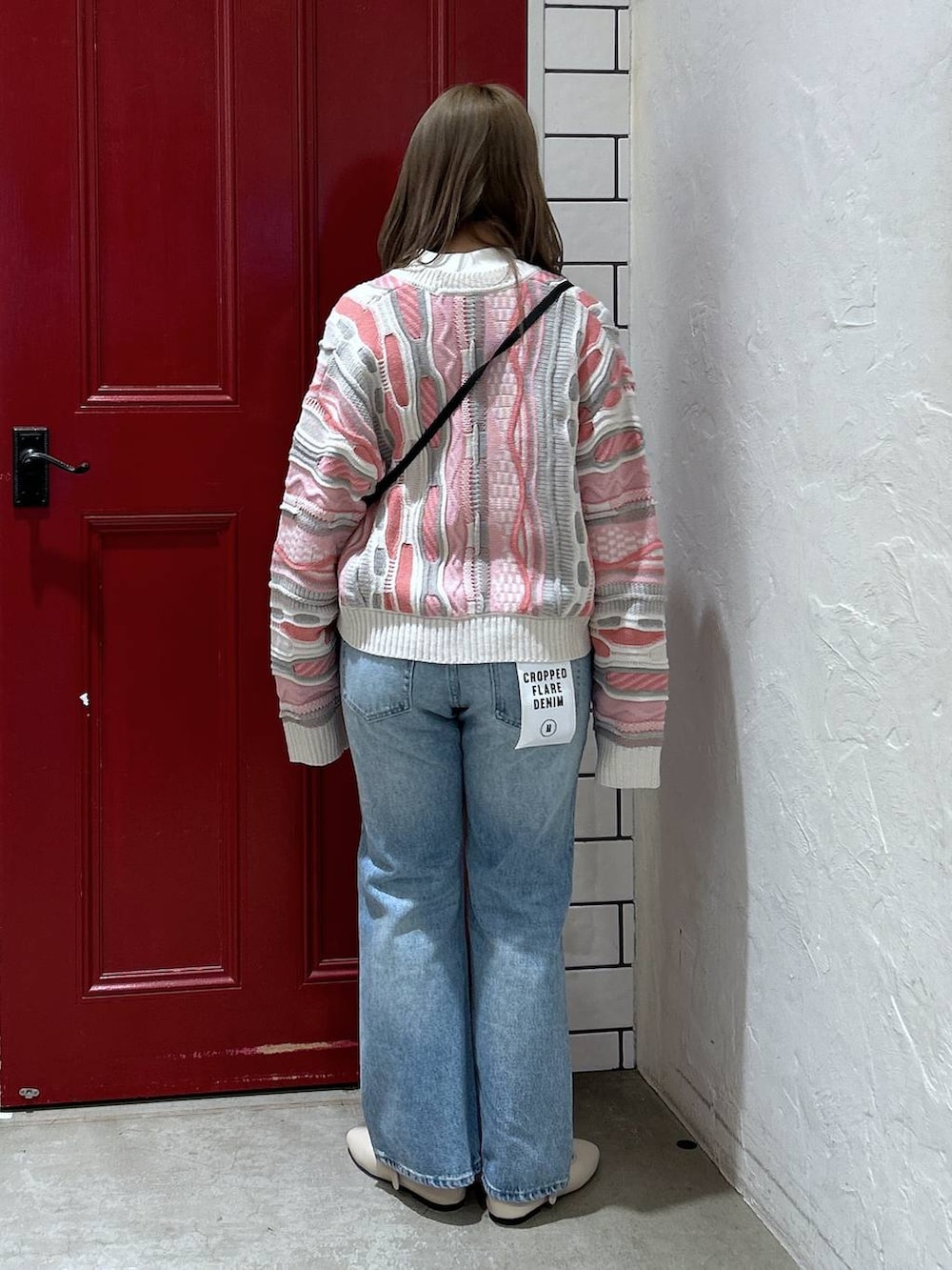 グレー系のショルダーバッグ、ホワイト系のパンプス、ブルー系のデニムパンツを着用したレディースの冬コーディネートの3枚目の写真