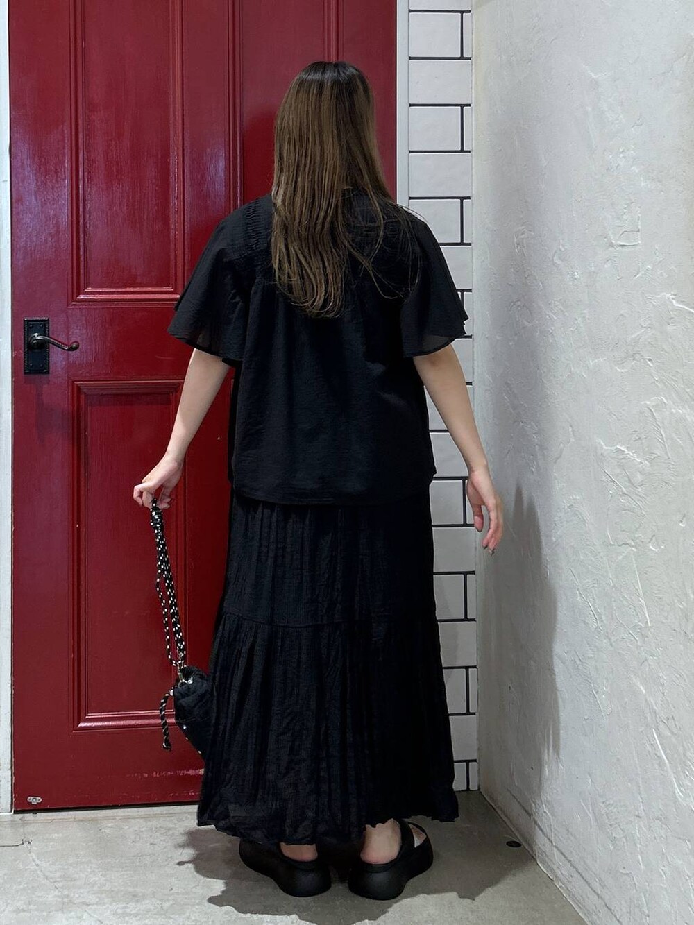 ブラック系のショルダーバッグ、ブラック系のサンダル、ブラック系のスカートを着用したレディースの夏コーディネートの4枚目の写真