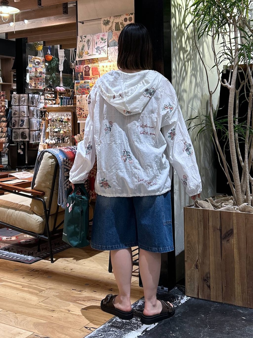 グリーン系のトートバッグ、レッド系のTシャツ/カットソー、ブラウン系のサンダルを着用したレディースの春コーディネートの4枚目の写真