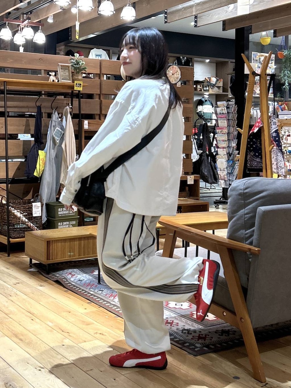 レッド系のスニーカー、ブラック系のショルダーバッグ、ベージュ系のカバーオールを着用したレディースの春コーディネートの3枚目の写真