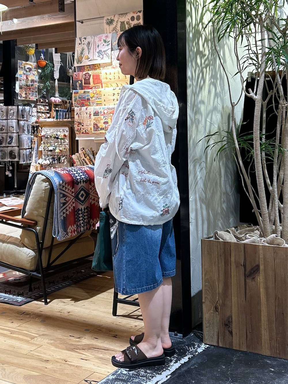 グリーン系のトートバッグ、レッド系のTシャツ/カットソー、ブラウン系のサンダルを着用したレディースの春コーディネートの3枚目の写真