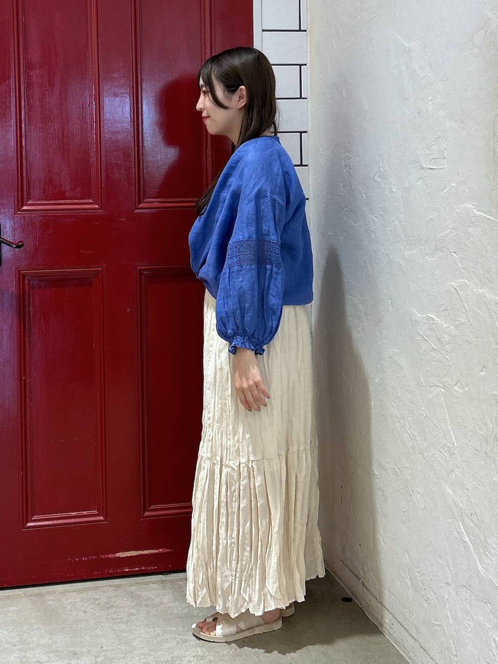 グレー系のショルダーバッグ、ベージュ系のスカート、ベージュ系のサンダルを着用したレディースの夏コーディネートの3枚目の写真