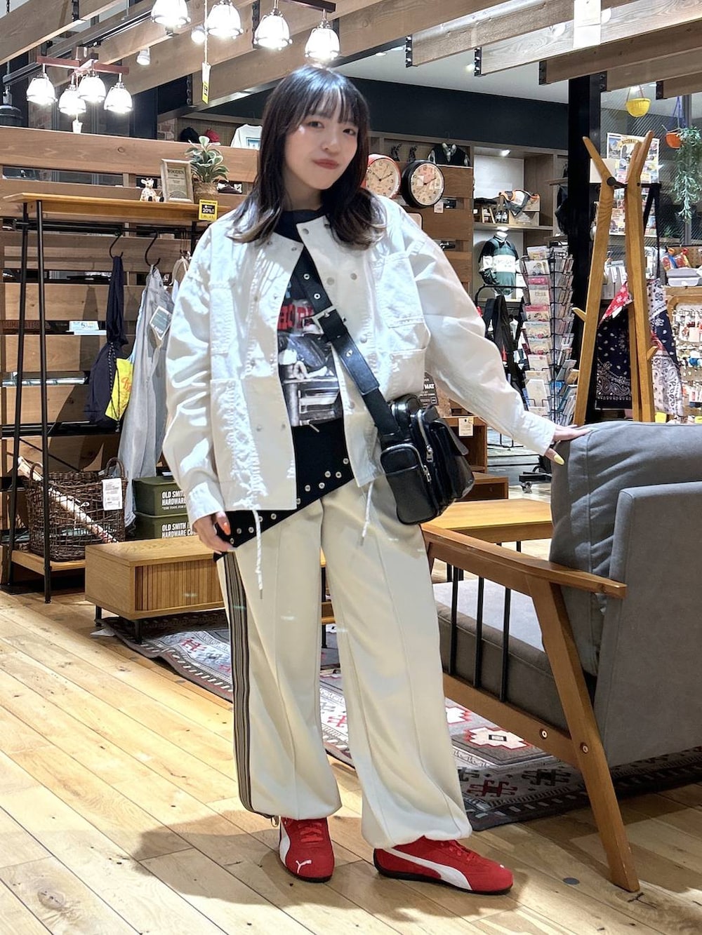 レッド系のスニーカー、ブラック系のショルダーバッグ、ベージュ系のカバーオールを着用したレディースの春コーディネートの2枚目の写真