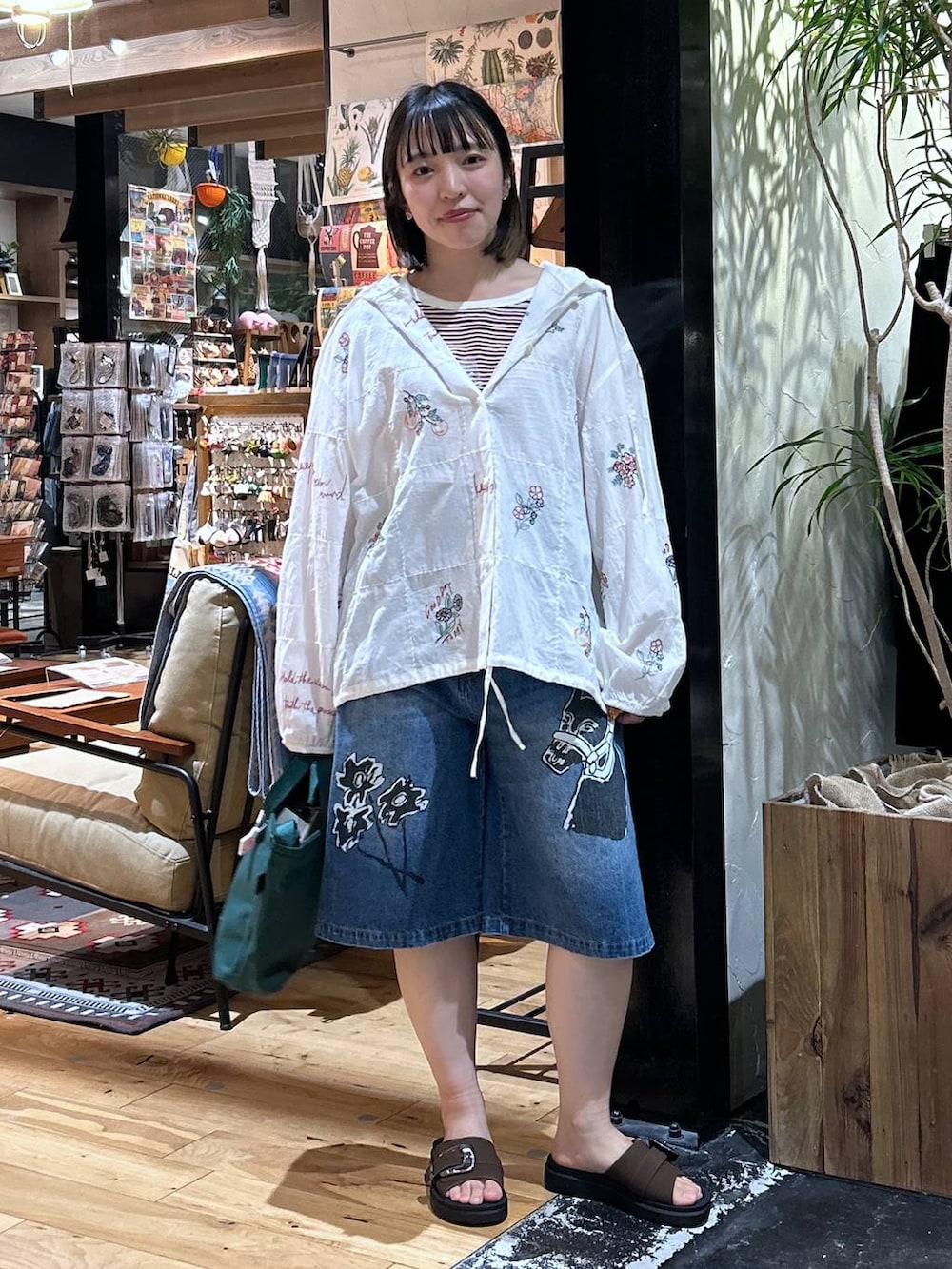 グリーン系のトートバッグ、レッド系のTシャツ/カットソー、ブラウン系のサンダルを着用したレディースの春コーディネートの2枚目の写真