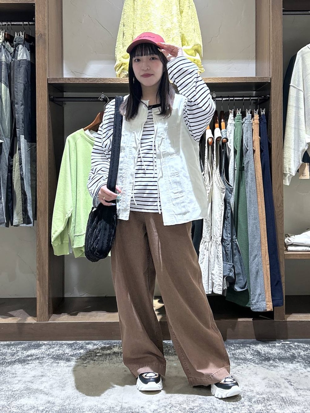 その他のスニーカー、ベージュ系のベスト、ブラック系のトートバッグを着用したレディースの春コーディネートの3枚目の写真