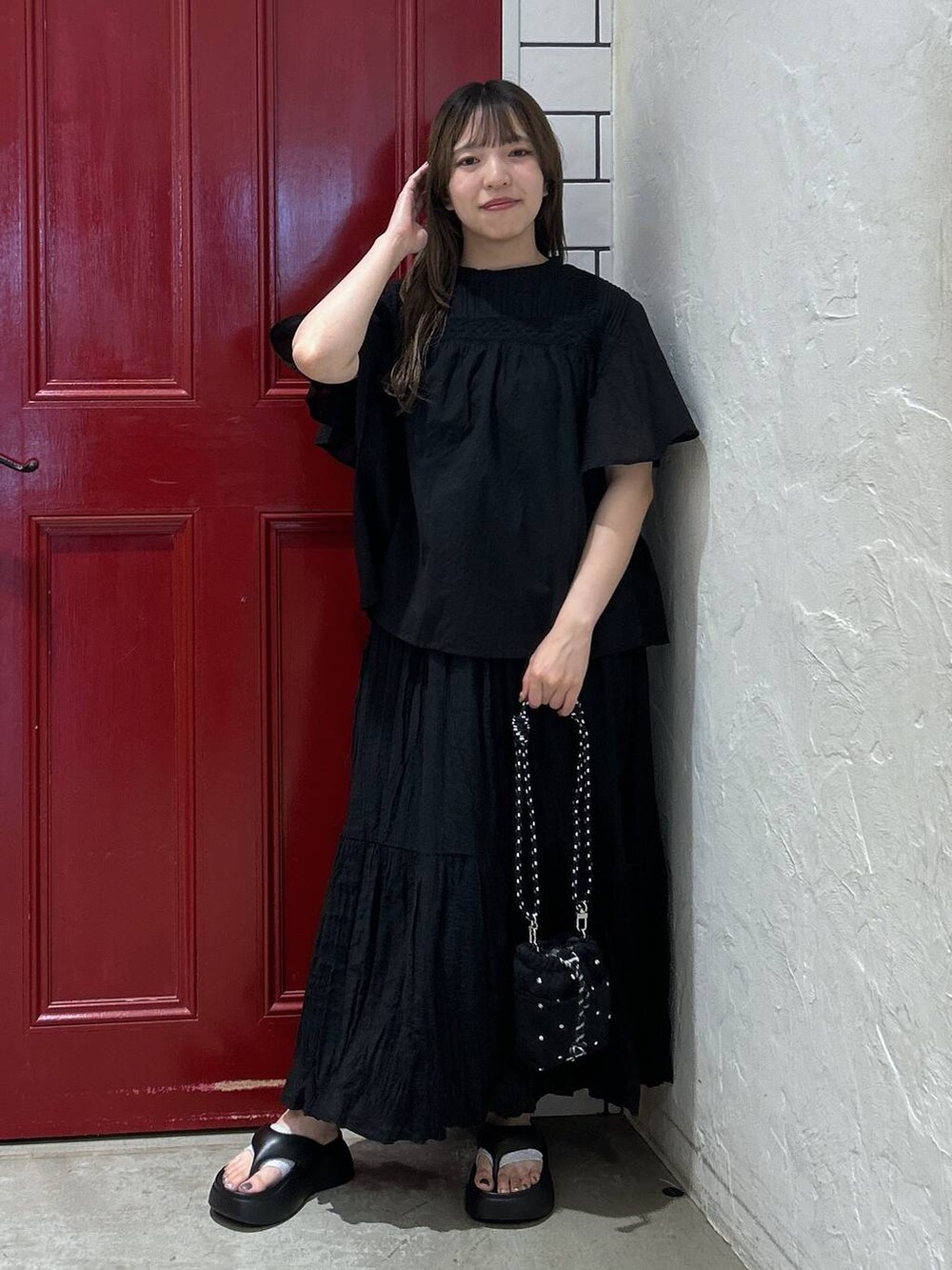 ブラック系のショルダーバッグ、ブラック系のサンダル、ブラック系のスカートを着用したレディースの夏コーディネートの2枚目の写真