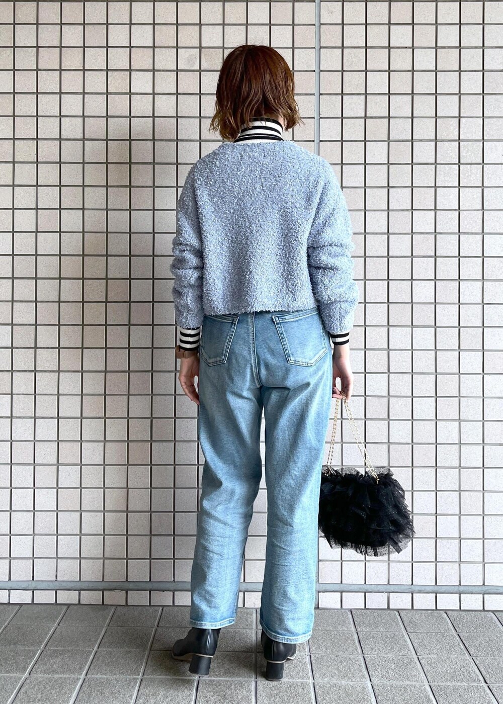 ブルー系のデニムパンツ、ブラック系のブーツ、ホワイト系のニット/セーターを着用したレディースの冬コーディネートの6枚目の写真