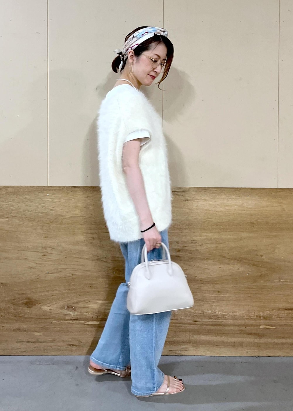 ベージュ系のボストンバッグ、ブルー系のデニムパンツ、ホワイト系のTシャツ/カットソーを着用したレディースの秋コーディネートの4枚目の写真