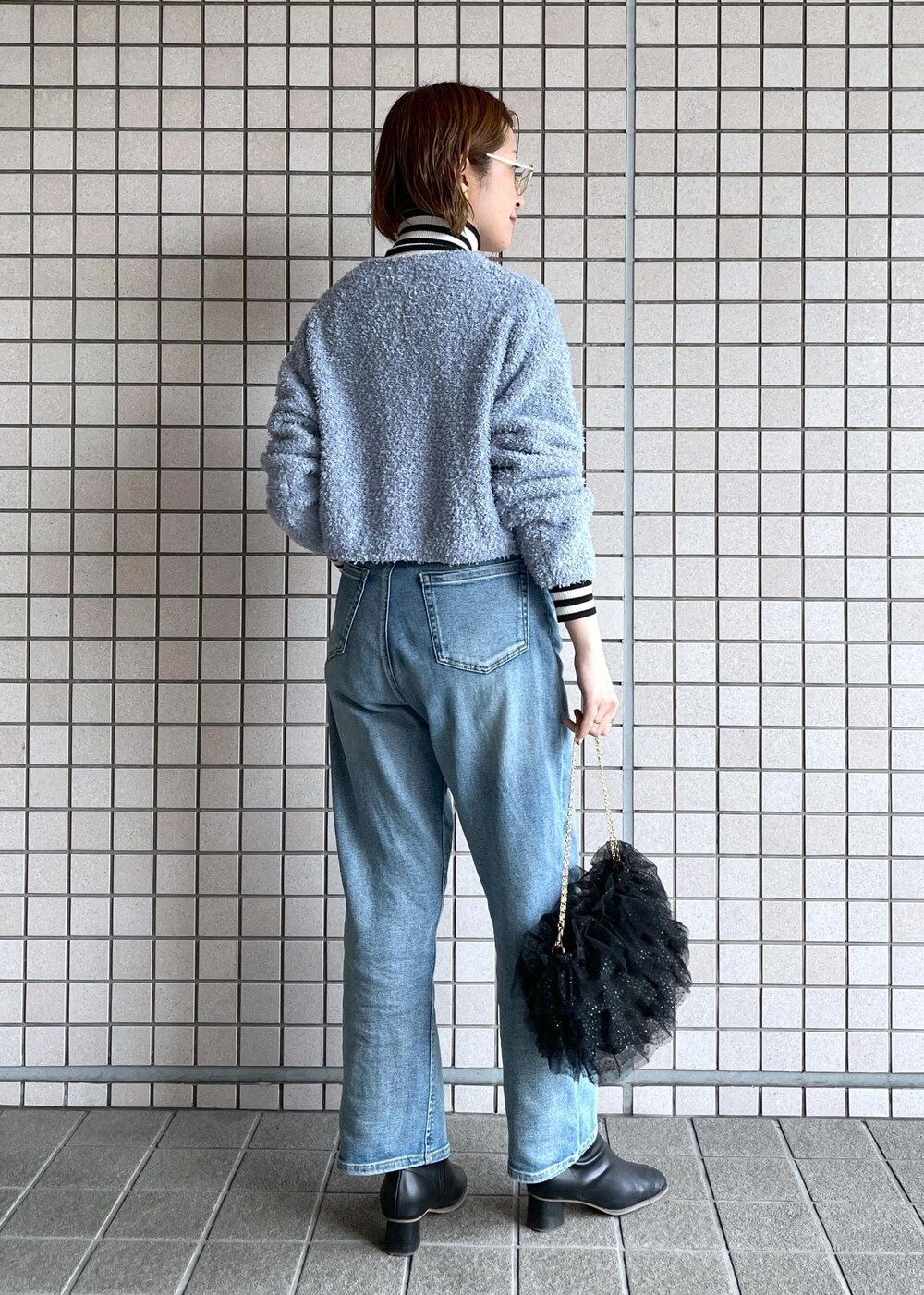 ブルー系のデニムパンツ、ブラック系のブーツ、ホワイト系のニット/セーターを着用したレディースの冬コーディネートの5枚目の写真