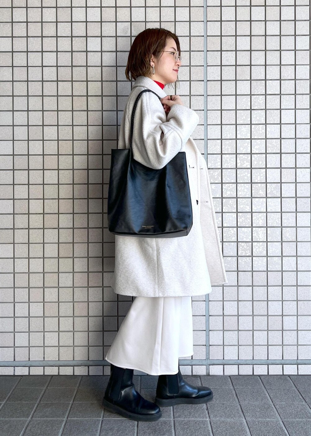 ブラック系のトートバッグ、レッド系のニット/セーター、ブラック系のブーツを着用したレディースの冬コーディネートの3枚目の写真