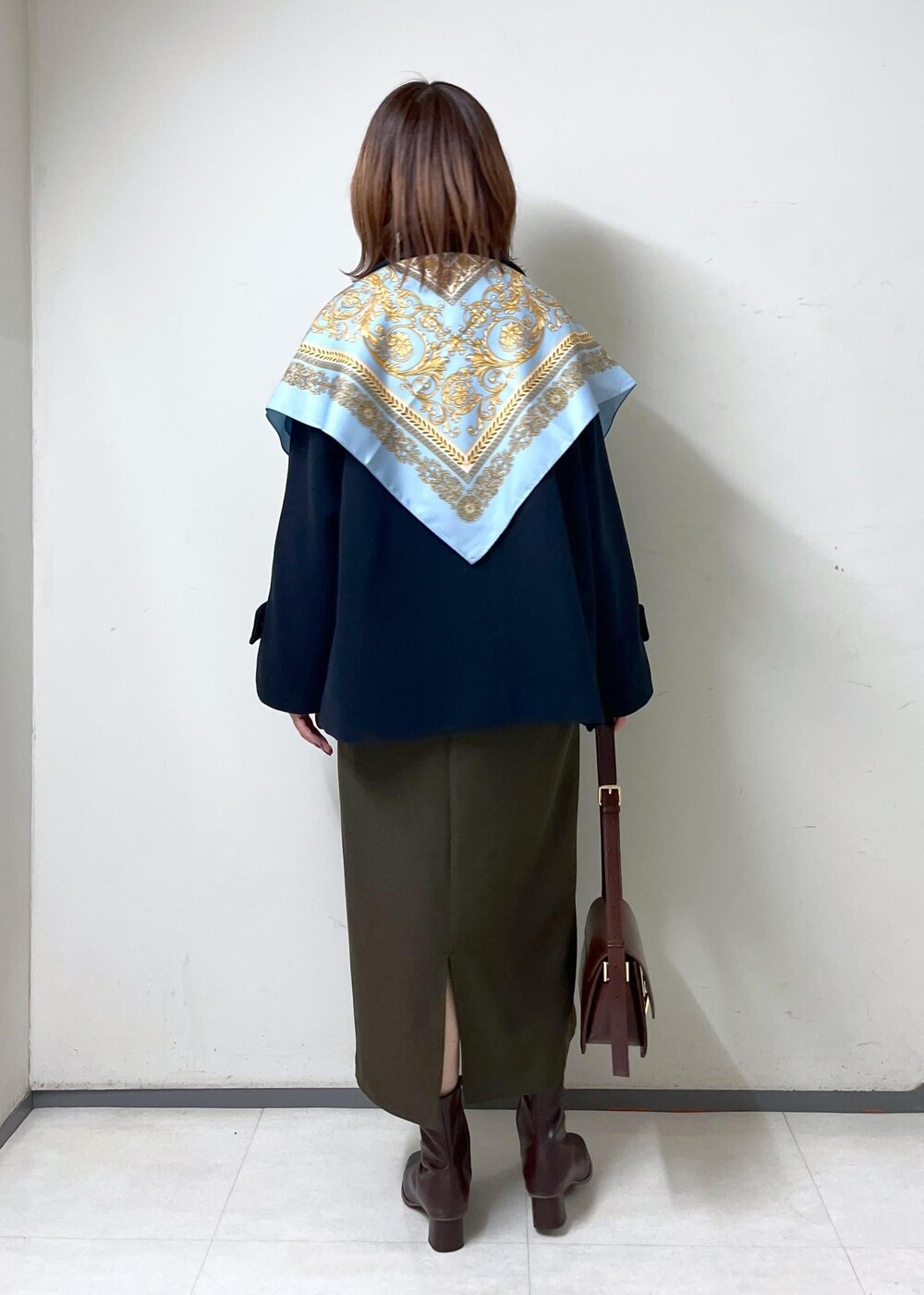 レッド系のショルダーバッグ、ホワイト系のニット/セーター、ブラウン系のブーツを着用したレディースの秋コーディネートの4枚目の写真