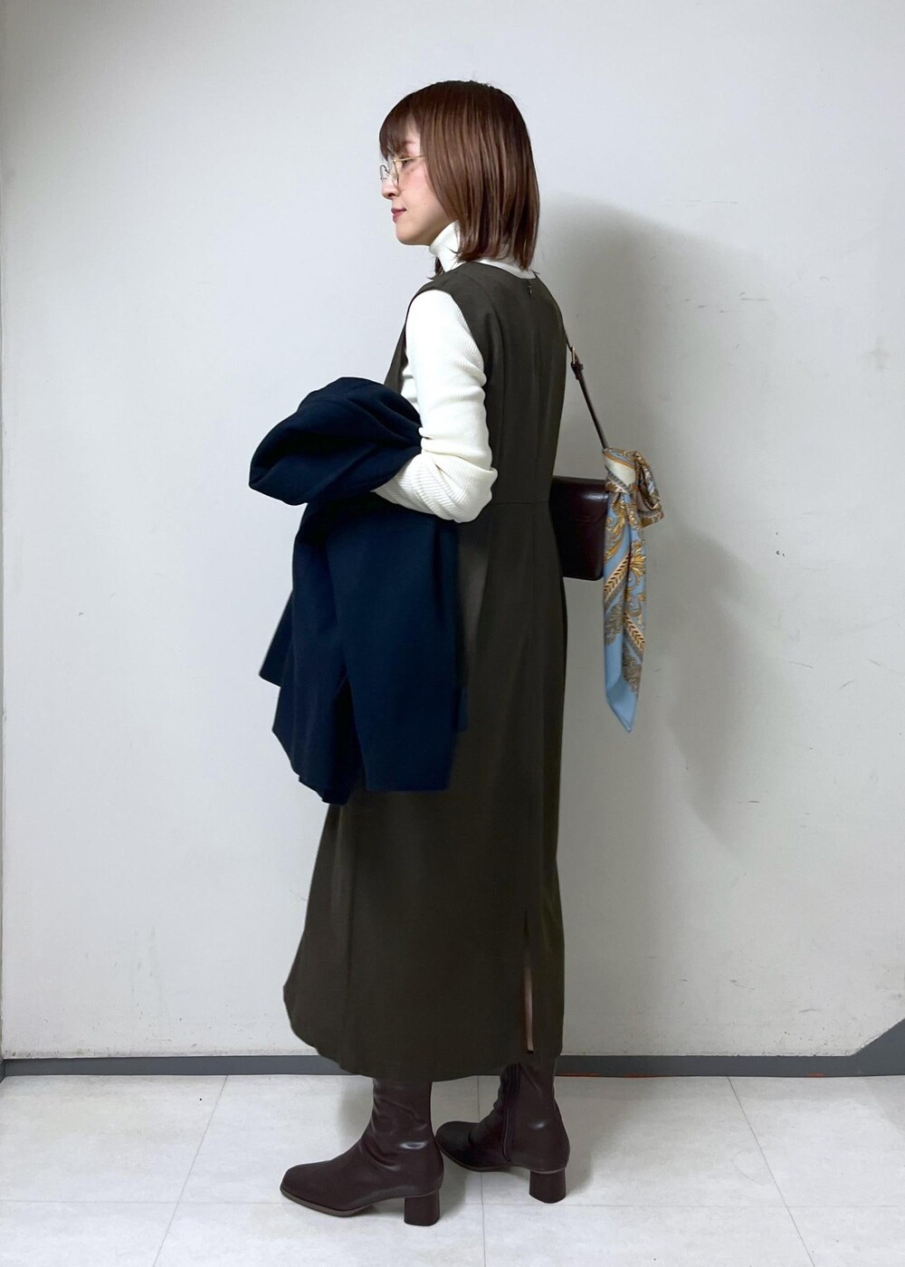 レッド系のショルダーバッグ、ホワイト系のニット/セーター、ブラウン系のブーツを着用したレディースの秋コーディネートの9枚目の写真