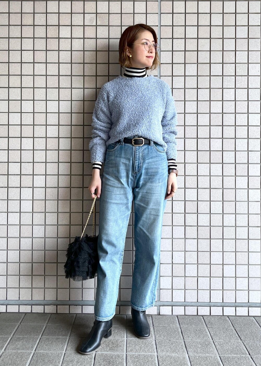 ブルー系のデニムパンツ、ブラック系のブーツ、ホワイト系のニット/セーターを着用したレディースの冬コーディネートの7枚目の写真