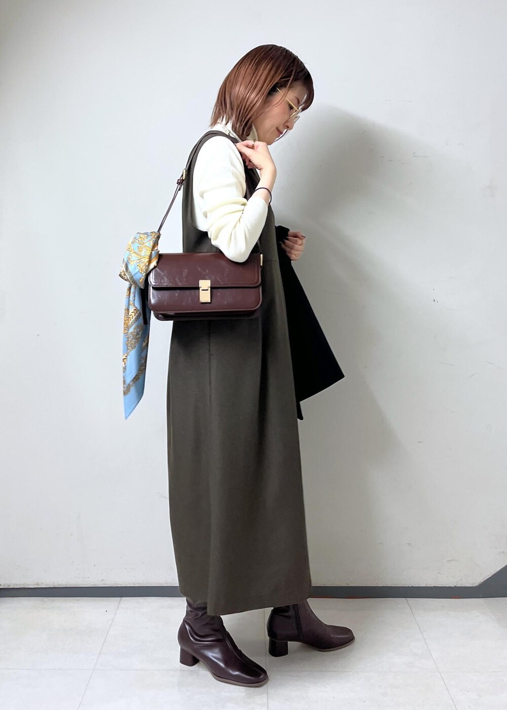 レッド系のショルダーバッグ、ホワイト系のニット/セーター、ブラウン系のブーツを着用したレディースの秋コーディネートの7枚目の写真