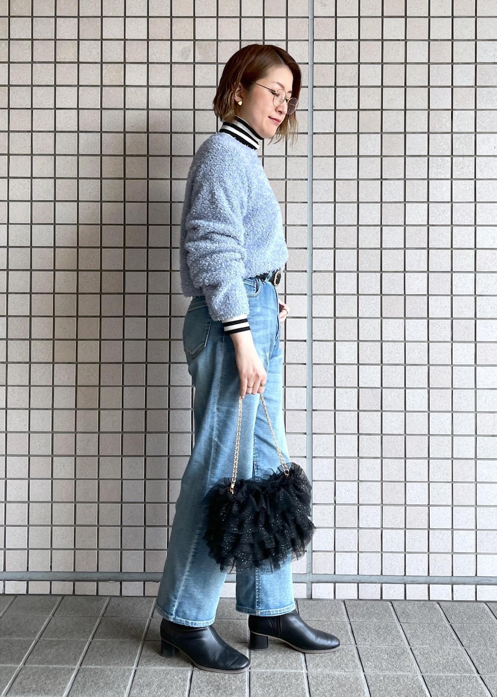 ブルー系のデニムパンツ、ブラック系のブーツ、ホワイト系のニット/セーターを着用したレディースの冬コーディネートの3枚目の写真