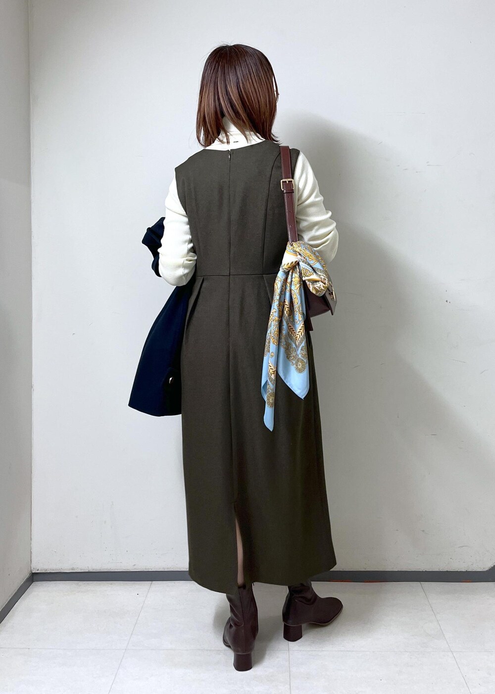 レッド系のショルダーバッグ、ホワイト系のニット/セーター、ブラウン系のブーツを着用したレディースの秋コーディネートの8枚目の写真