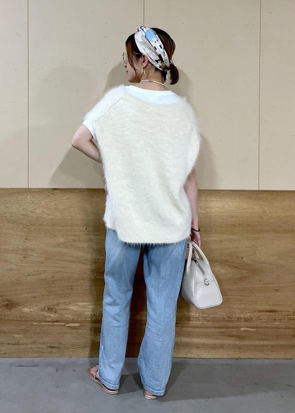 ベージュ系のボストンバッグ、ブルー系のデニムパンツ、ホワイト系のTシャツ/カットソーを着用したレディースの秋コーディネートの5枚目の写真