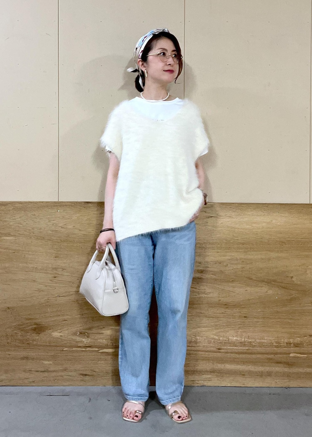 ベージュ系のボストンバッグ、ブルー系のデニムパンツ、ホワイト系のTシャツ/カットソーを着用したレディースの秋コーディネートの3枚目の写真