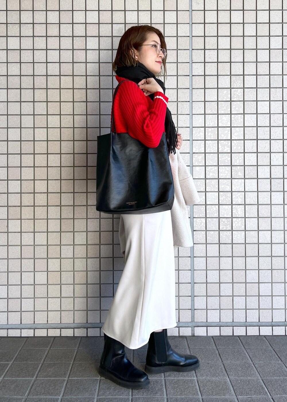 ブラック系のトートバッグ、レッド系のニット/セーター、ブラック系のブーツを着用したレディースの冬コーディネートの6枚目の写真
