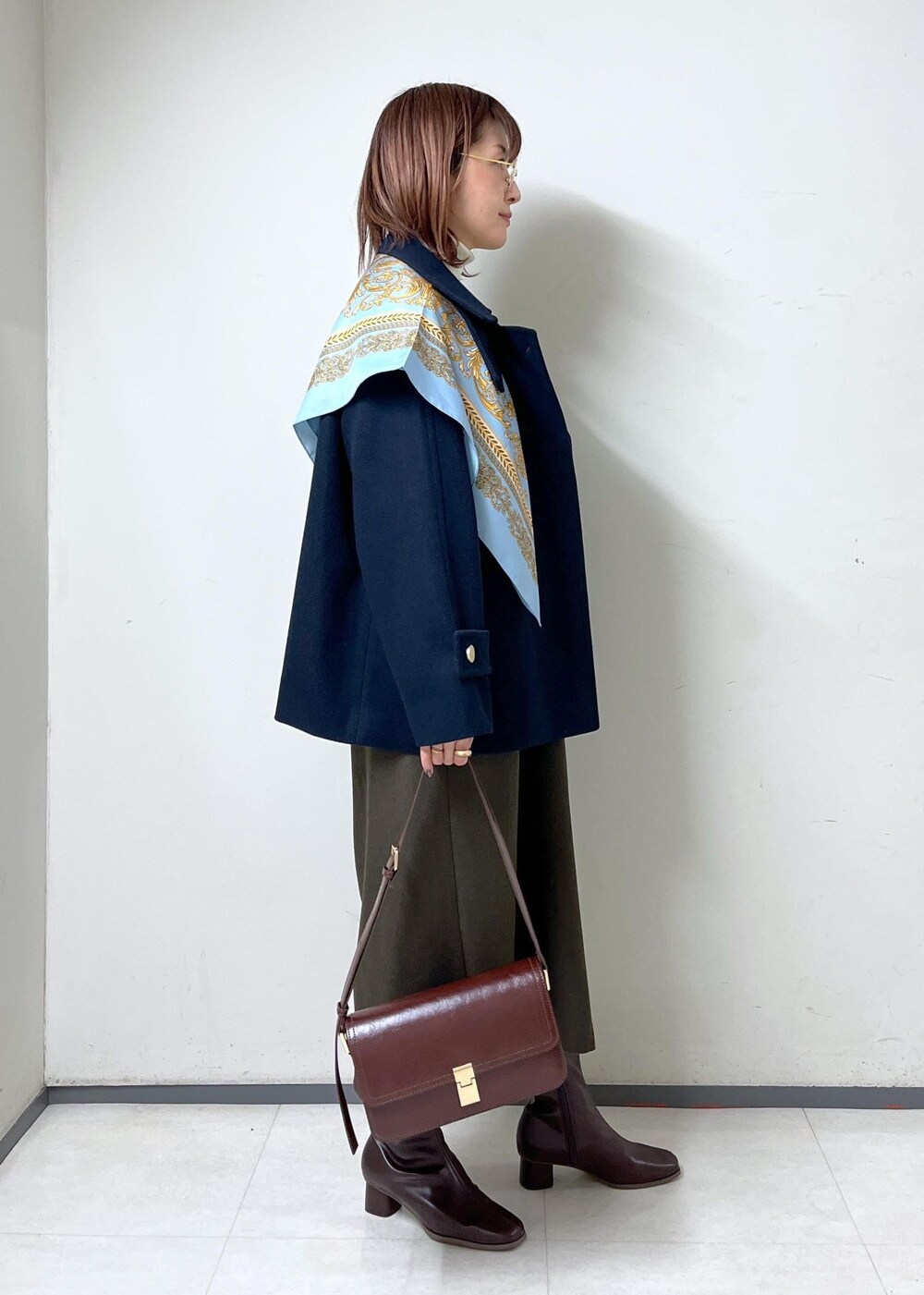 レッド系のショルダーバッグ、ホワイト系のニット/セーター、ブラウン系のブーツを着用したレディースの秋コーディネートの3枚目の写真