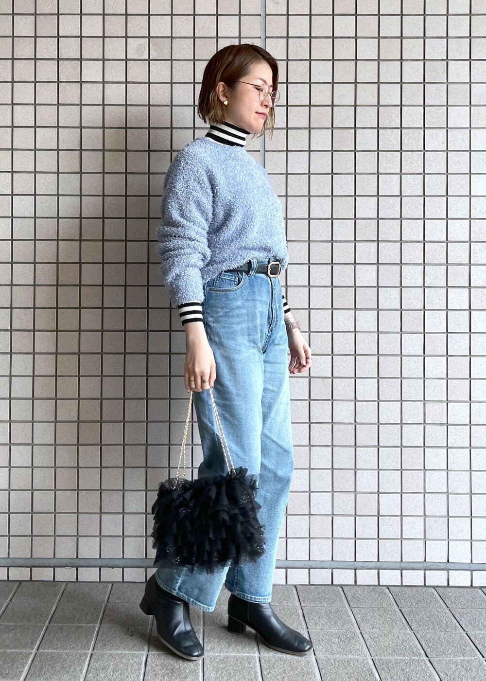 ブルー系のデニムパンツ、ブラック系のブーツ、ホワイト系のニット/セーターを着用したレディースの冬コーディネートの2枚目の写真