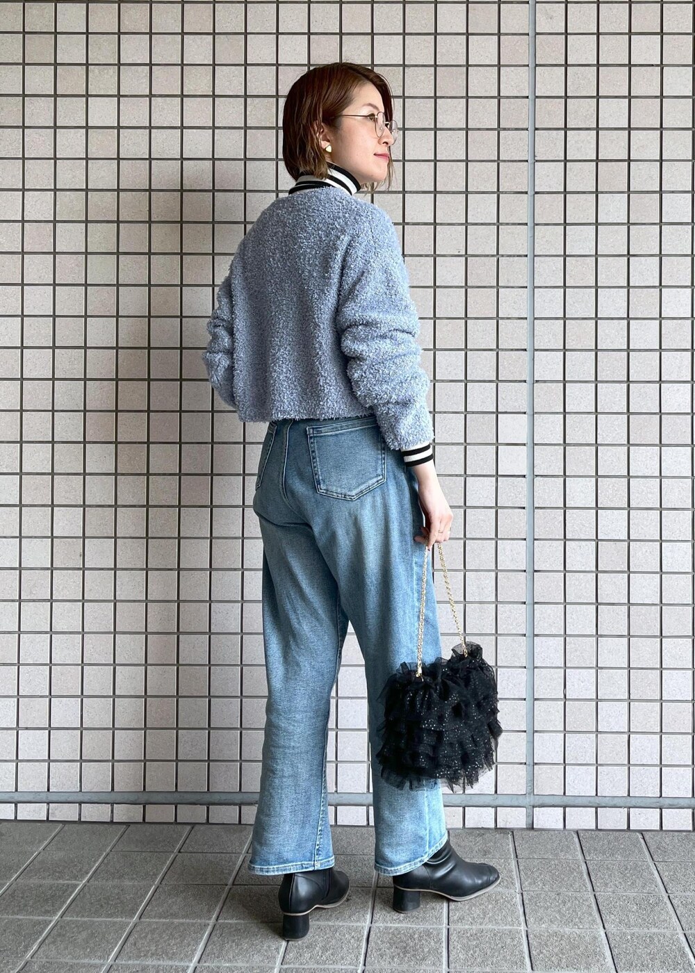 ブルー系のデニムパンツ、ブラック系のブーツ、ホワイト系のニット/セーターを着用したレディースの冬コーディネートの4枚目の写真