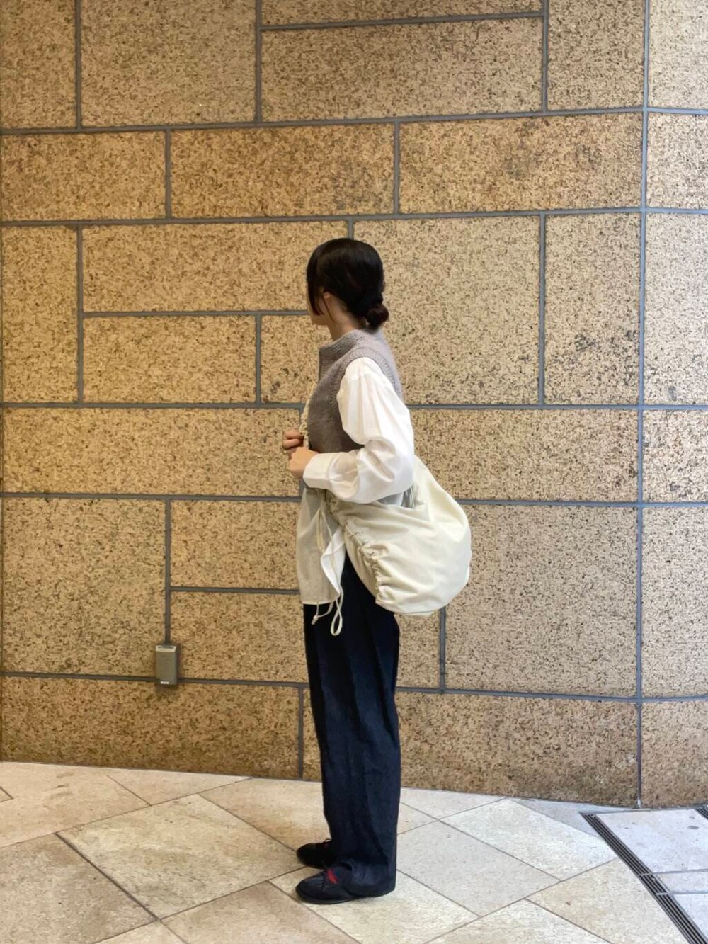 ブルー系のデニムパンツ、ブラック系のバレエシューズ、ホワイト系のショルダーバッグを着用したレディースの秋コーディネートの5枚目の写真