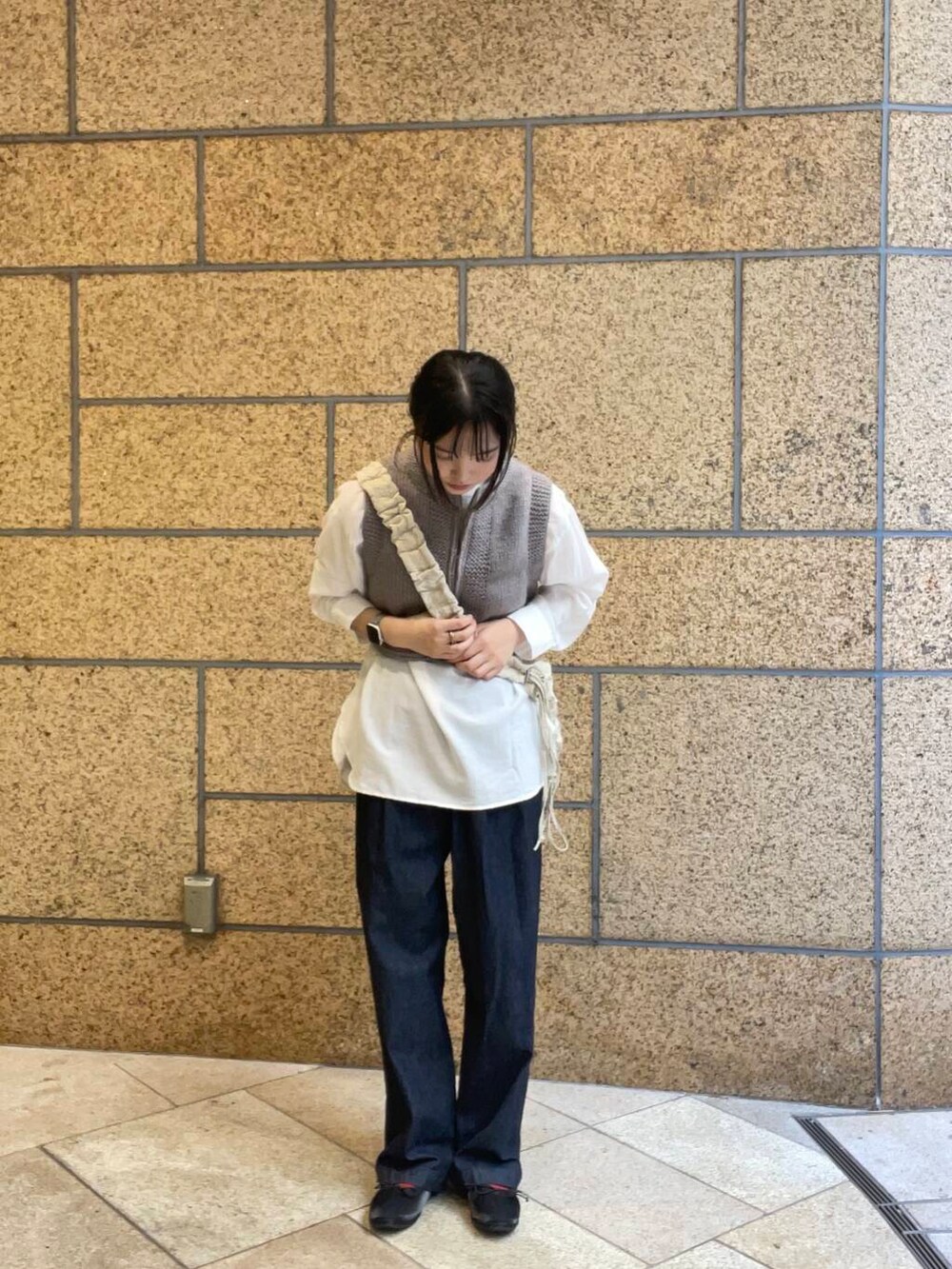 ブルー系のデニムパンツ、ブラック系のバレエシューズ、ホワイト系のショルダーバッグを着用したレディースの秋コーディネートの2枚目の写真