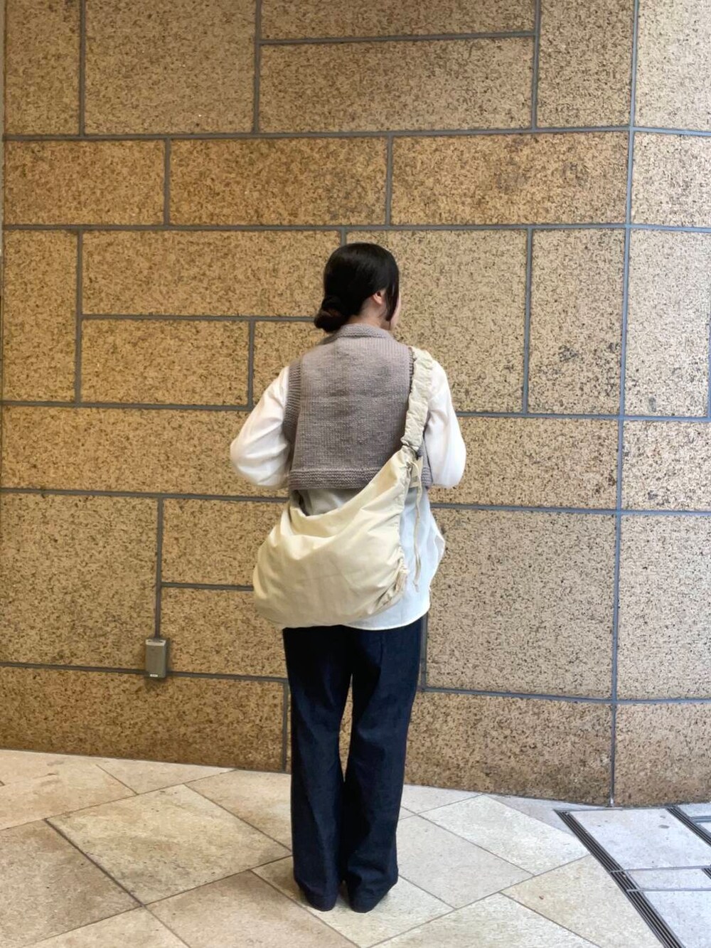 ブルー系のデニムパンツ、ブラック系のバレエシューズ、ホワイト系のショルダーバッグを着用したレディースの秋コーディネートの4枚目の写真