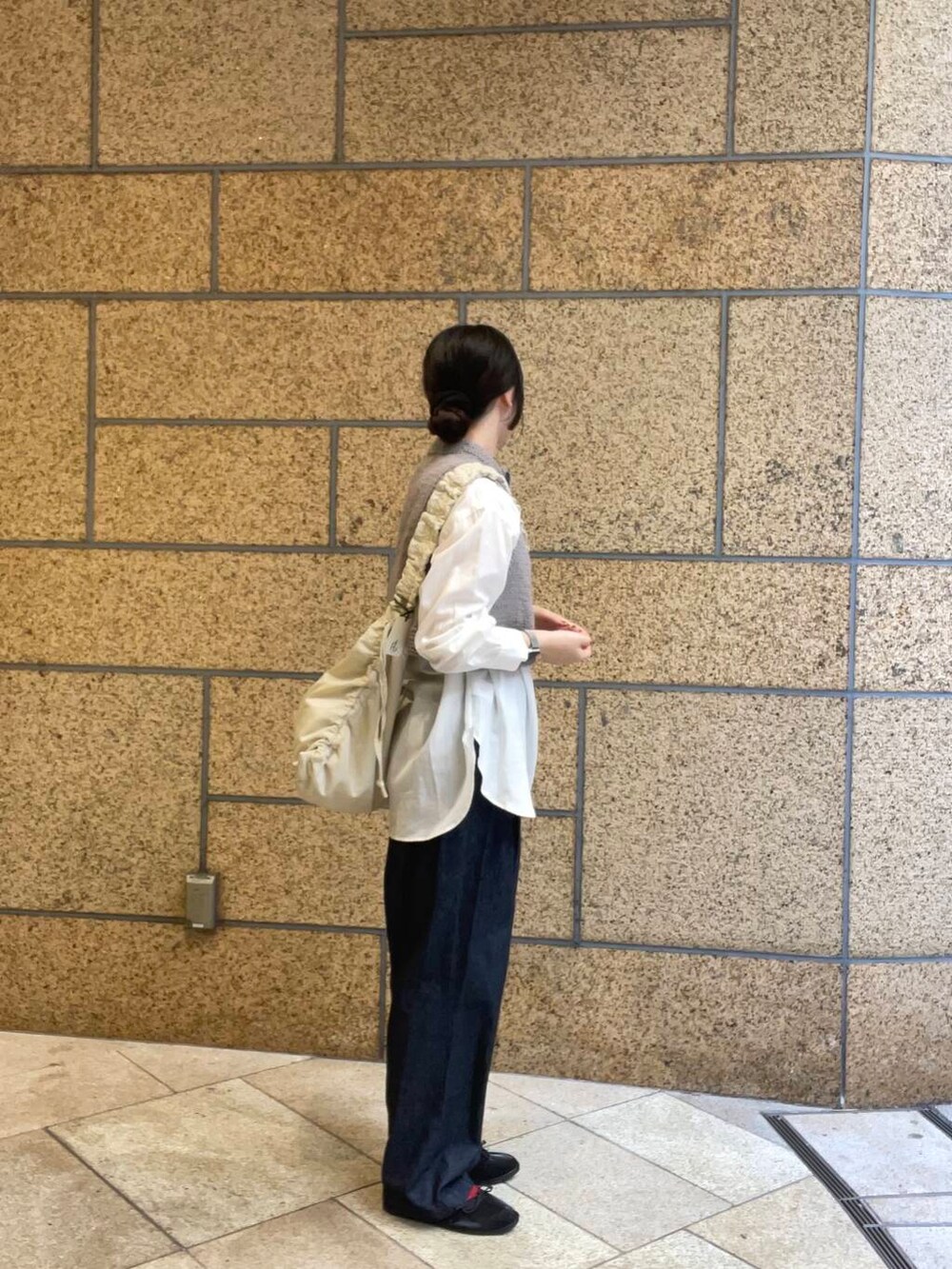 ブルー系のデニムパンツ、ブラック系のバレエシューズ、ホワイト系のショルダーバッグを着用したレディースの秋コーディネートの3枚目の写真