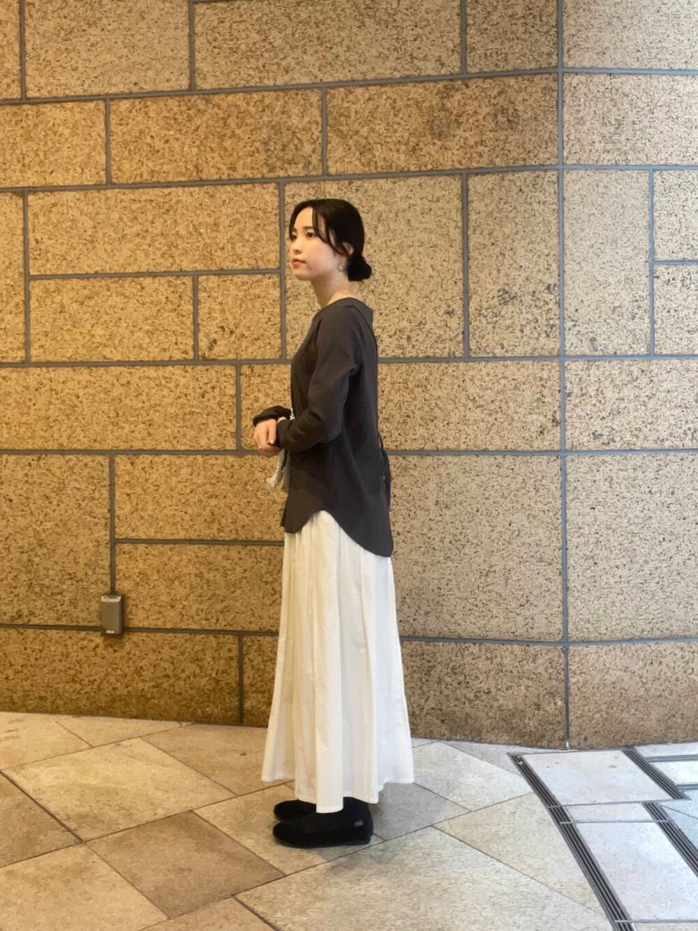 シルバー系のハンドバッグ、ホワイト系のスカート、ブラック系のバレエシューズを着用したレディースの夏コーディネートの4枚目の写真