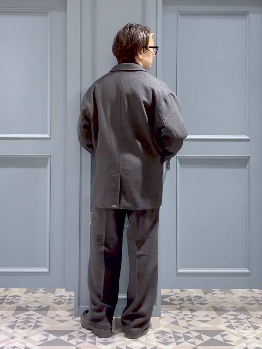 グレー系のニット/セーター、ブラック系のドレスシューズ、グレー系のテーラードジャケットを着用したメンズの秋コーディネートの3枚目の写真