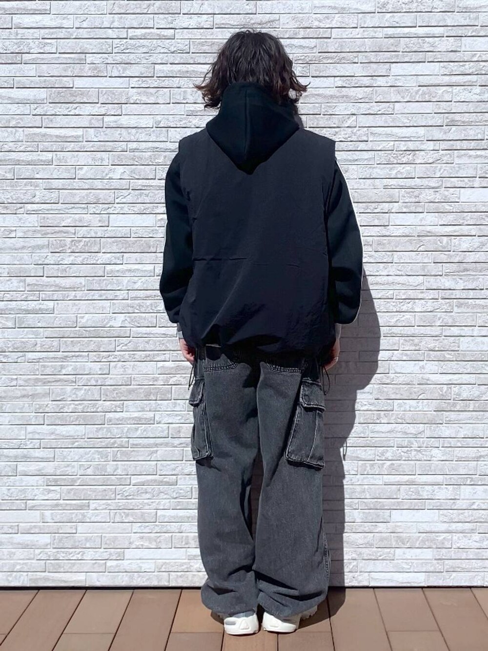 グレー系のデニムパンツ、ブラック系のナイロンジャケット、ブラック系のパーカーを着用したメンズの春コーディネートの3枚目の写真
